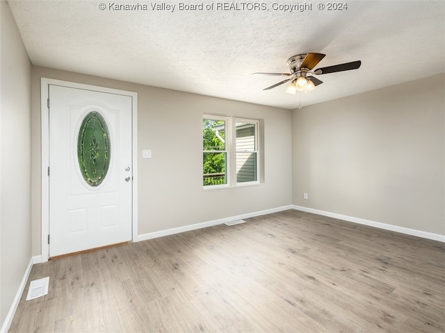 foyer with ceiling fan, a textured ceiling, and light hardwood / wood-style flooring