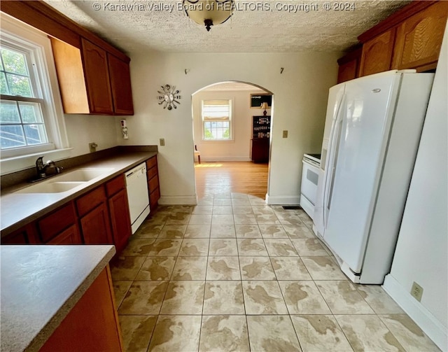 kitchen featuring light tile patterned floors, white appliances, sink, and a textured ceiling