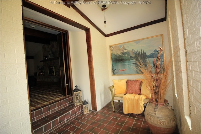 sitting room featuring ornamental molding, lofted ceiling, and dark tile patterned floors