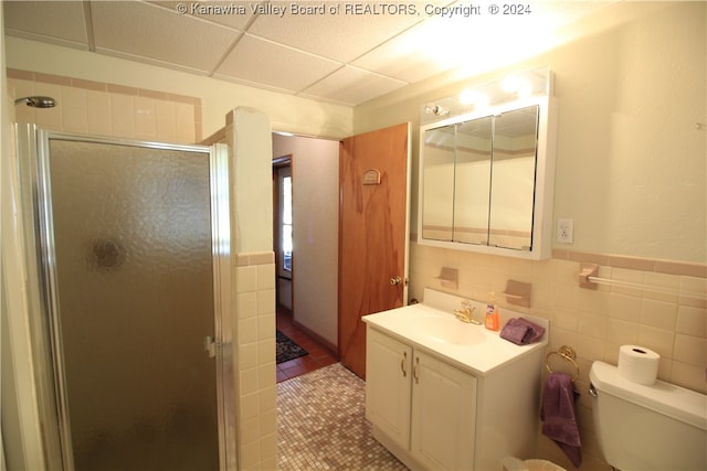 bathroom featuring vanity, an enclosed shower, tile walls, toilet, and tile patterned floors