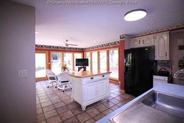 kitchen featuring light tile patterned flooring, kitchen peninsula, ceiling fan, and black fridge