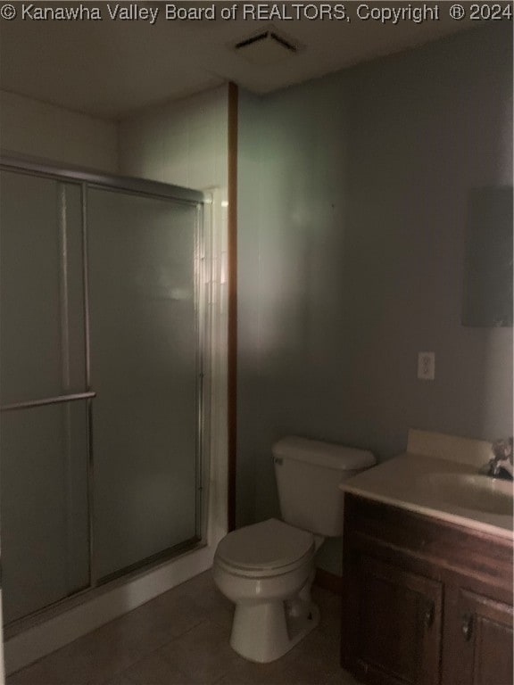 bathroom featuring tile patterned flooring, vanity, toilet, and an enclosed shower