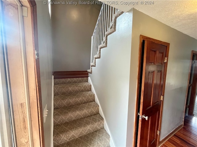 stairway featuring hardwood / wood-style flooring and a textured ceiling