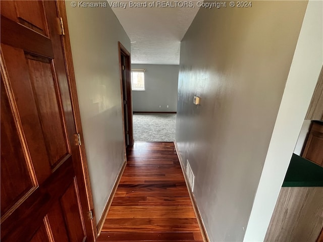 hall featuring a textured ceiling and dark hardwood / wood-style floors