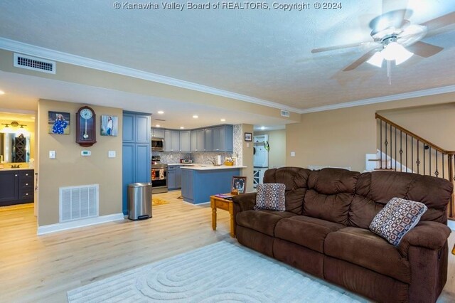 living room with light wood-type flooring, a textured ceiling, ornamental molding, and ceiling fan