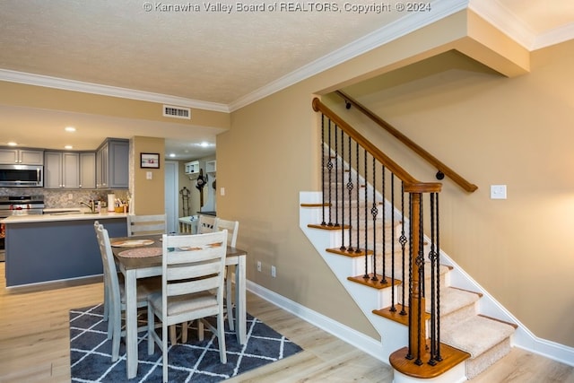 dining space featuring light hardwood / wood-style floors, crown molding, and a textured ceiling