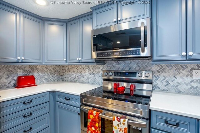 kitchen featuring blue cabinets, a textured ceiling, appliances with stainless steel finishes, and tasteful backsplash