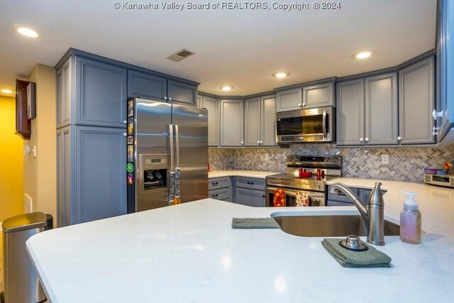 kitchen with decorative backsplash, kitchen peninsula, and stainless steel appliances