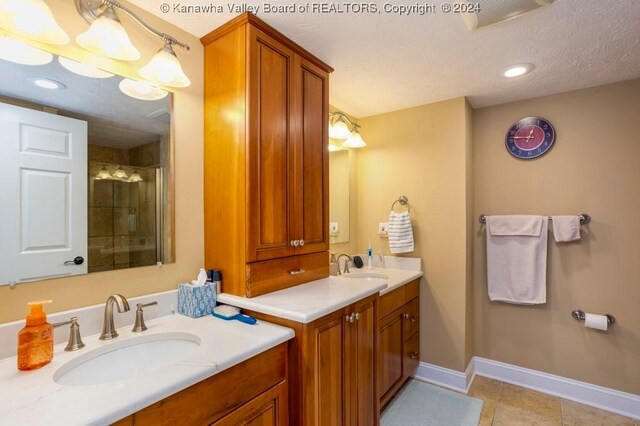 bathroom featuring tile patterned flooring, a textured ceiling, walk in shower, and vanity