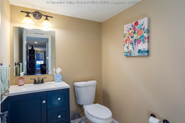 bathroom with a textured ceiling, vanity, and toilet