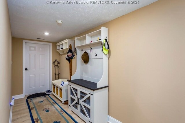 mudroom with light hardwood / wood-style flooring and a textured ceiling