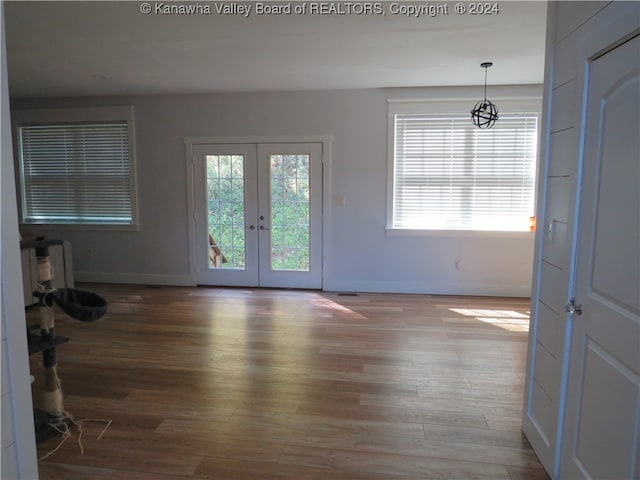 unfurnished living room featuring a healthy amount of sunlight, hardwood / wood-style floors, and french doors