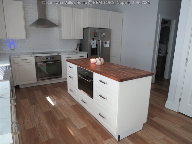 kitchen featuring white cabinets, wooden counters, wood-type flooring, wall chimney exhaust hood, and black appliances