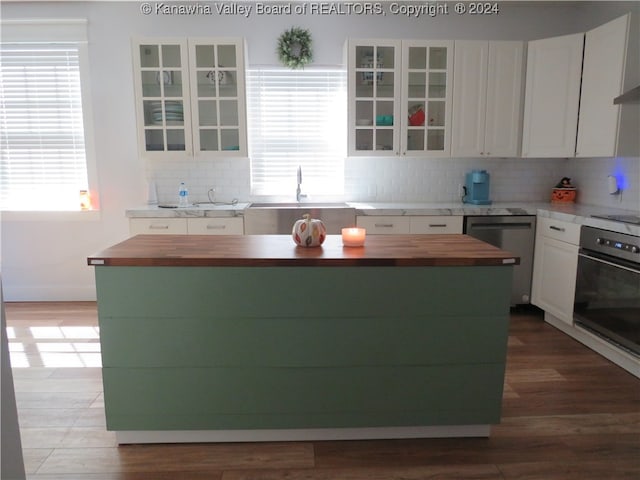 kitchen with wood-type flooring, tasteful backsplash, sink, white cabinets, and black appliances