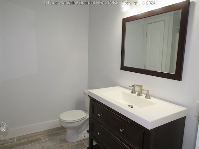 bathroom featuring wood-type flooring, vanity, and toilet