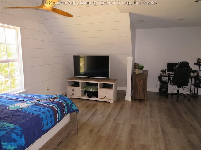 bedroom with wood walls, hardwood / wood-style floors, and ceiling fan