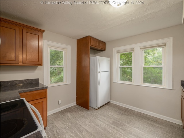 kitchen with a textured ceiling, range, light hardwood / wood-style flooring, and white refrigerator