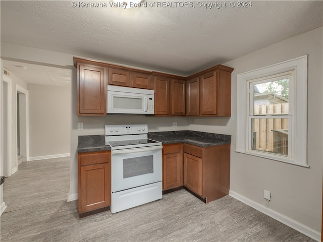 kitchen featuring a textured ceiling, white appliances, and light hardwood / wood-style flooring