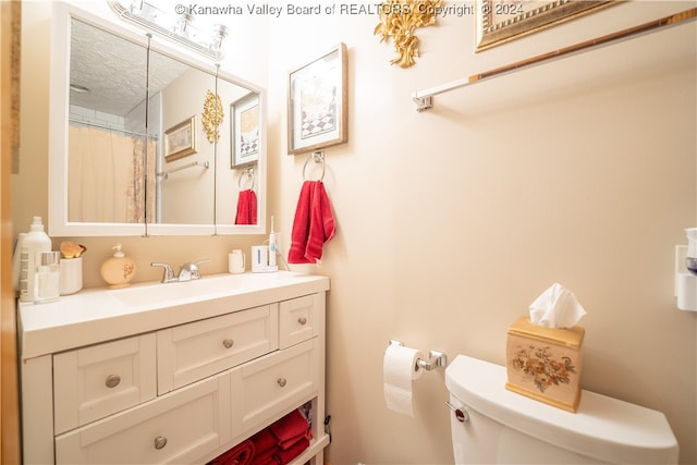 bathroom featuring a textured ceiling, curtained shower, vanity, and toilet