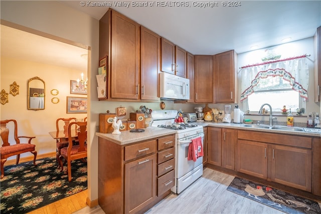 kitchen with light wood-type flooring, sink, and white appliances