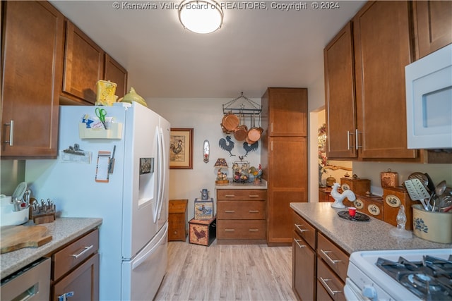 kitchen featuring white appliances, light hardwood / wood-style flooring, and light stone counters