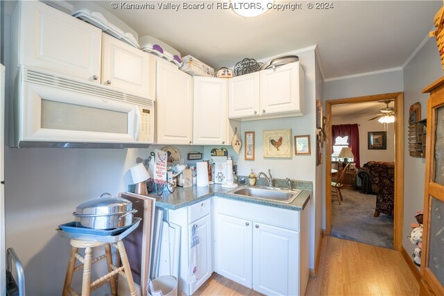 kitchen with ceiling fan, white cabinets, ornamental molding, sink, and light hardwood / wood-style floors