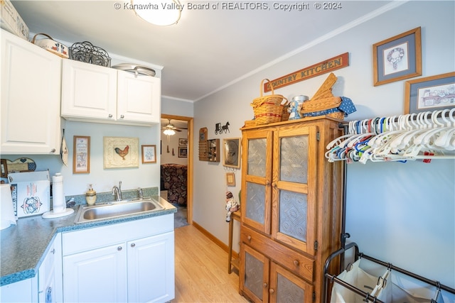 kitchen with ceiling fan, white cabinets, sink, light wood-type flooring, and crown molding