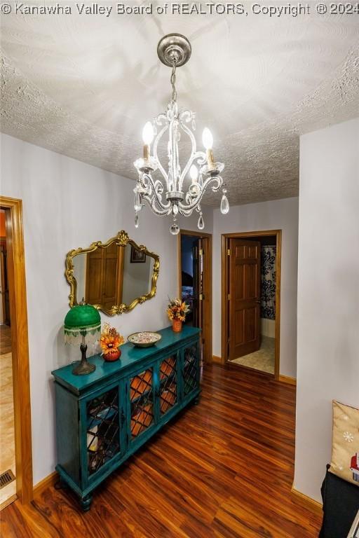 hallway with dark hardwood / wood-style flooring, a chandelier, and a textured ceiling