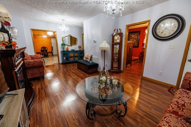 living room featuring a notable chandelier, dark wood-type flooring, and a textured ceiling