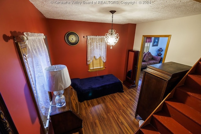 bedroom featuring an inviting chandelier, wood-type flooring, and a textured ceiling