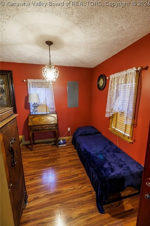 bedroom with wood-type flooring, electric panel, and a textured ceiling