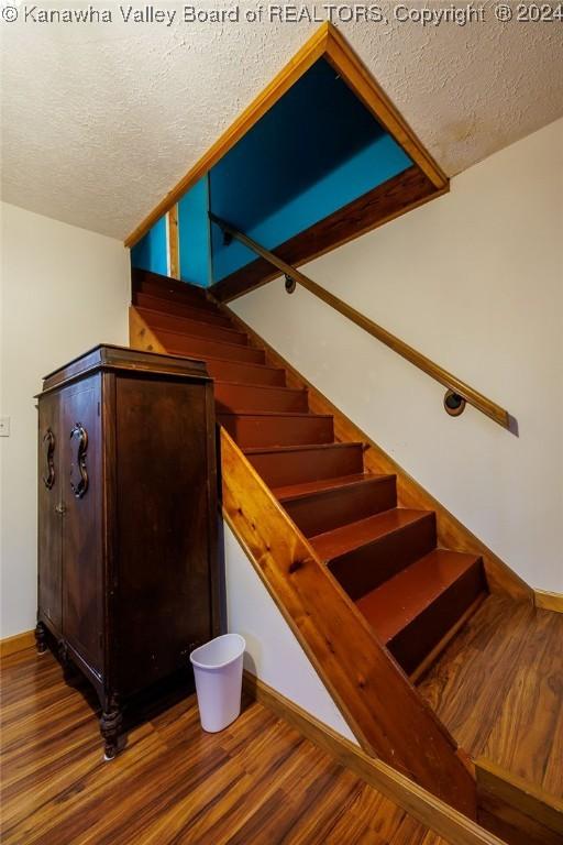 stairs with hardwood / wood-style floors and a textured ceiling