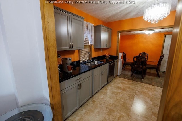 kitchen with gray cabinetry, dishwasher, sink, and a notable chandelier