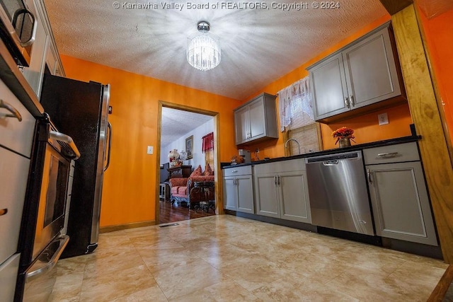 kitchen featuring pendant lighting, appliances with stainless steel finishes, gray cabinets, and a chandelier