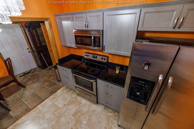 kitchen with dark stone countertops, stainless steel appliances, and gray cabinetry