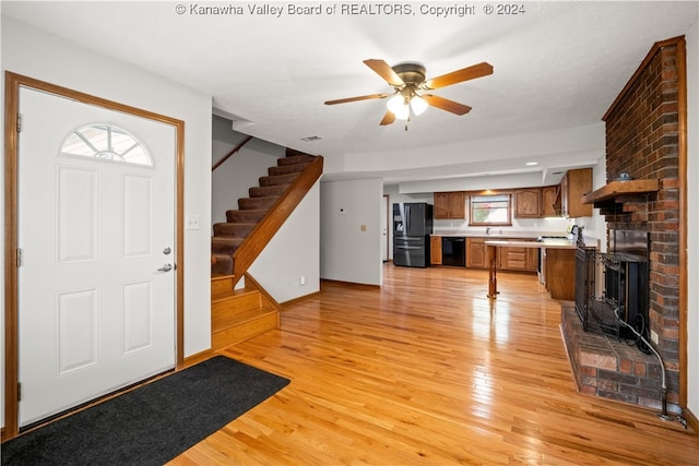 entrance foyer featuring a brick fireplace, light wood-type flooring, ceiling fan, and sink