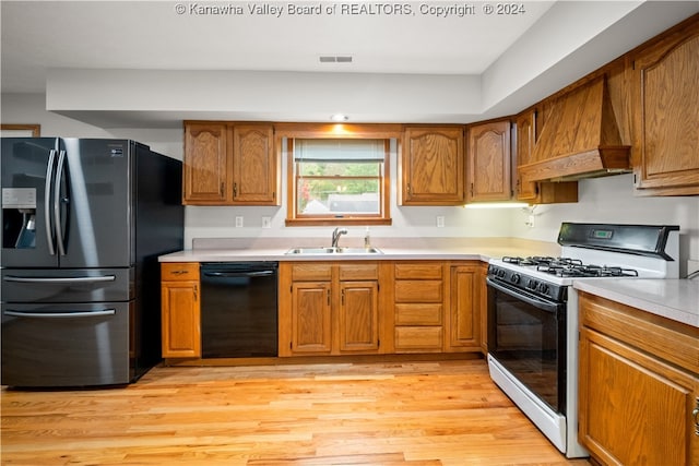 kitchen featuring black dishwasher, light hardwood / wood-style flooring, white gas range, sink, and stainless steel fridge with ice dispenser