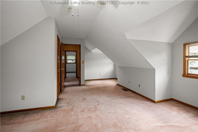 bonus room with vaulted ceiling and light colored carpet