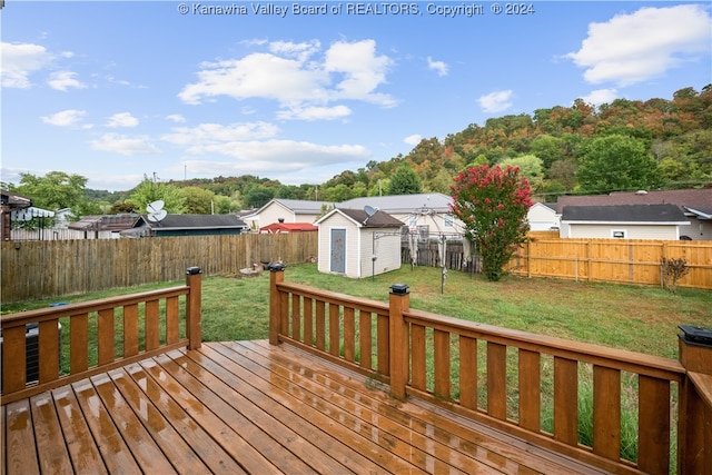 wooden deck featuring a storage shed and a lawn