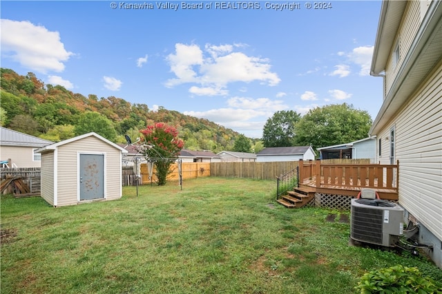 view of yard with central AC unit, a wooden deck, and a shed