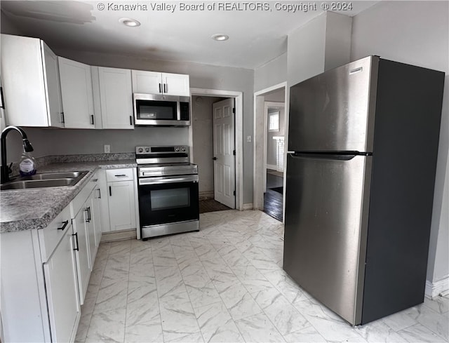 kitchen with stainless steel appliances, sink, and white cabinetry