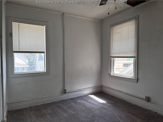 empty room featuring dark carpet, a textured ceiling, and a healthy amount of sunlight