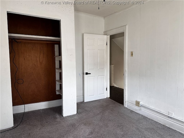 unfurnished bedroom with wooden walls and dark colored carpet