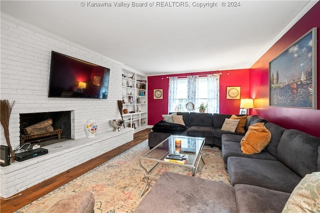 living room with hardwood / wood-style floors, a brick fireplace, built in shelves, and crown molding