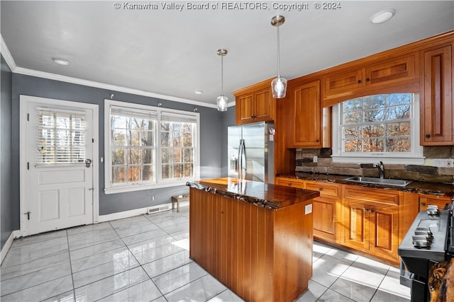 kitchen with sink, a kitchen island, a healthy amount of sunlight, and stainless steel refrigerator with ice dispenser