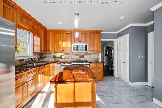 kitchen featuring sink, crown molding, decorative light fixtures, a kitchen island, and stainless steel appliances