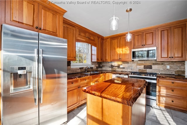 kitchen featuring stainless steel appliances, sink, decorative light fixtures, dark stone countertops, and a center island