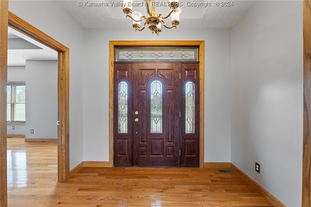 foyer featuring a textured ceiling, light hardwood / wood-style floors, and a chandelier