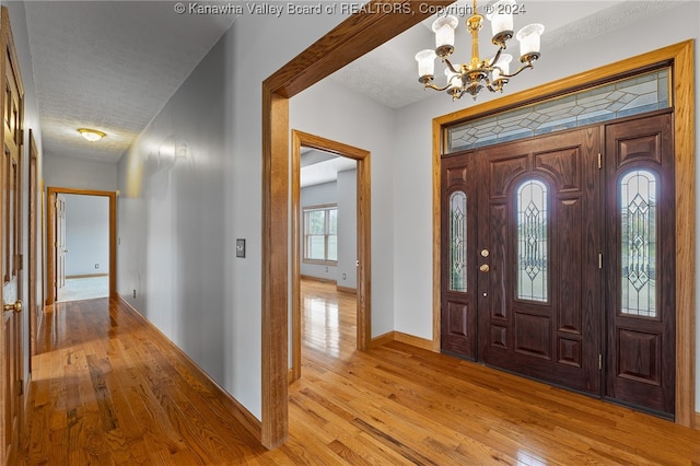 foyer entrance with a textured ceiling, a chandelier, and light hardwood / wood-style floors