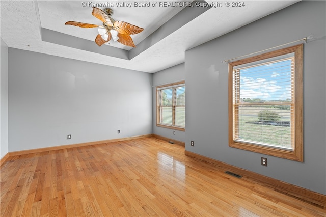 unfurnished room with ceiling fan, light wood-type flooring, and a wealth of natural light